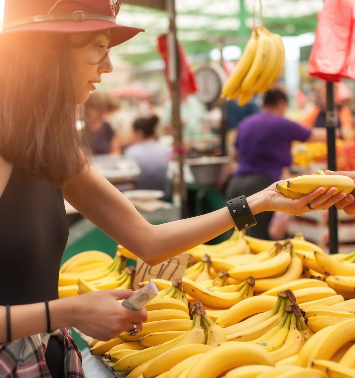 Una donna acquista un casco di banane al mercato